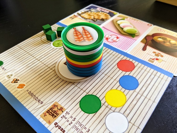 A stack of sushi. You can also see a couple of the side dish cards, and a couple of wasabi cubes in the background.