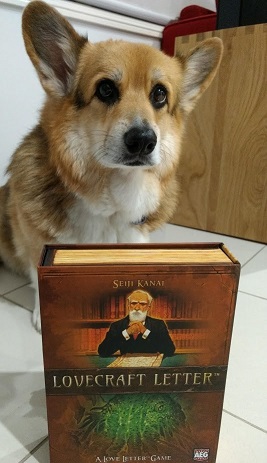Chester the corgi sitting behind the Lovecraft Letter game box.