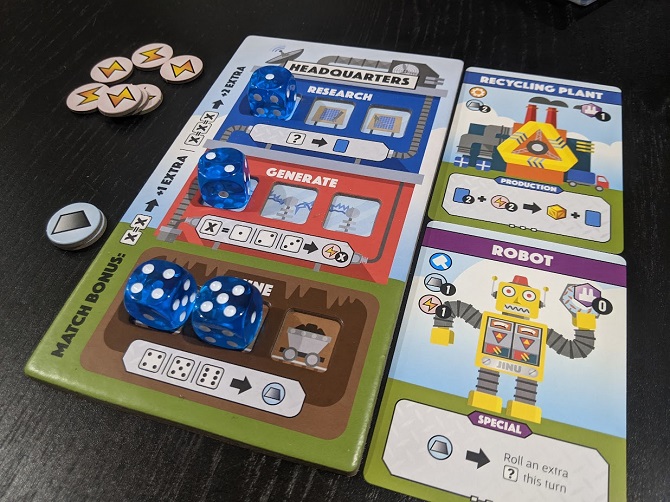 Shows the Robot card, and the Recycling Plant card. As well as a player's HQ with dice and some resources to the side.