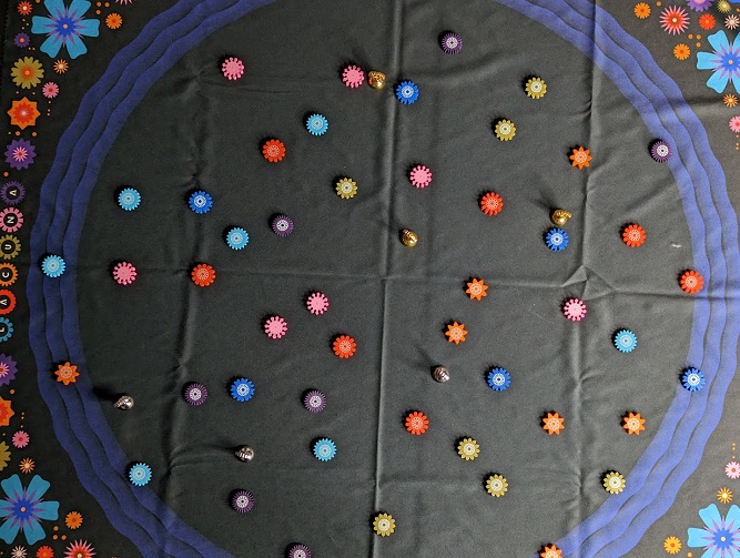 Shows the playmat which is black, with a large blue circle around the centre. Beyond the circle are beautiful flowers