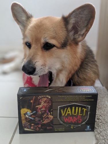 Cute yawning corgi sitting behind box of Vault Wars