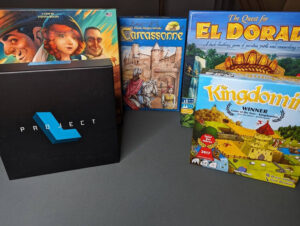 The following board games standing up on display: Camel Up, Project L, Carcassonne, The Quest for El Dorado and Kingdomino