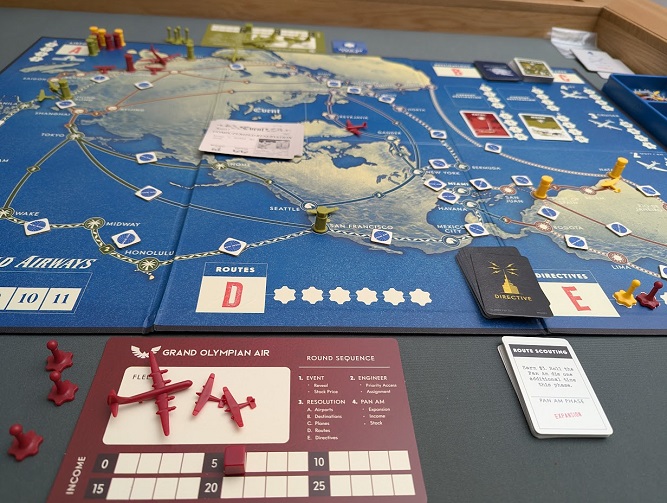 A Pan Am game in progress, showing the world map board covered in routes and tokens, with a player's airline mat and cards in the foreground.