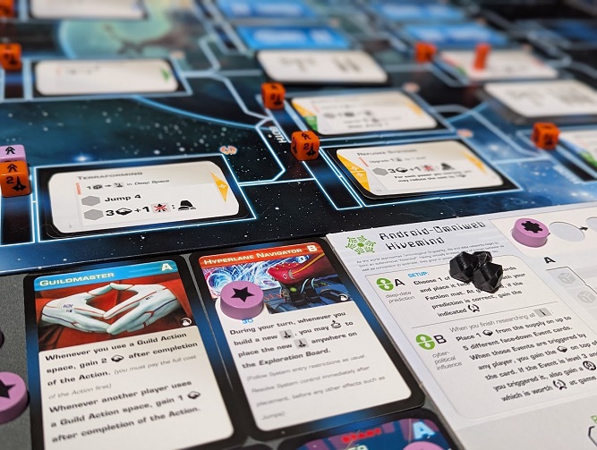 A close-up of a game of Beyond the Sun in progress. Several orange cube markers sit on space technology cards, while the Android-Omniweb Hivemind board rests beside red and blue leader cards.