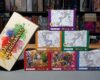 The white Dale of Merchants 10th Anniversary main collection box is angled on the left. Stacked beside it are six numbered tuck boxes featuring distinct animalfolk illustrations and colour schemes.